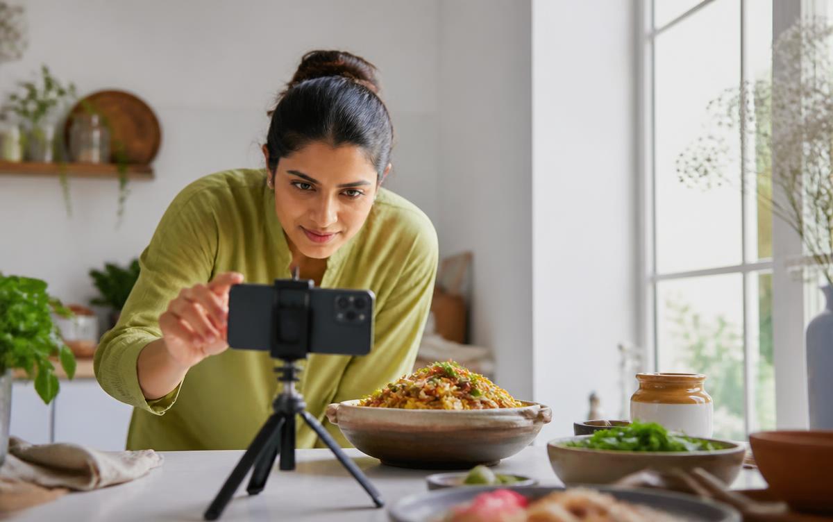 Filming a plated Indian dish on a smartphone tripod for restaurant social media content